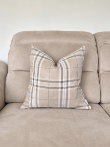 Beżowa sofa z kraciastą poduszką.png
