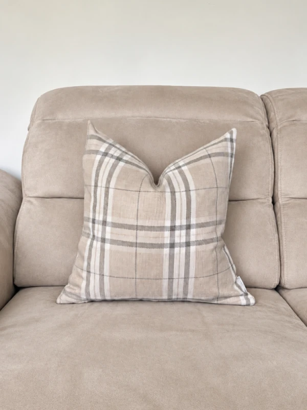 Beżowa sofa z kraciastą poduszką.png