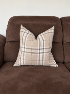 Czekoladowa sofa z kraciastą poduszką.png