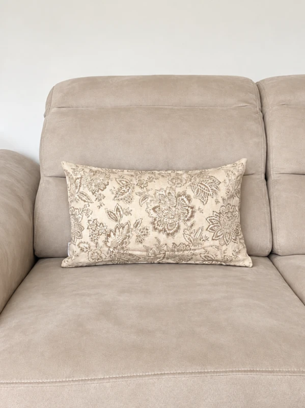Beżowa sofa z ozdobną poduszką i lampą.png